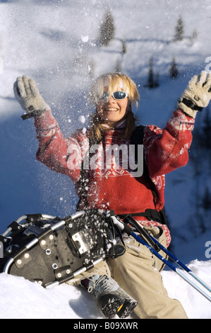 young woman with snow shoes, throwing snow into the air, France, Alps Stock Photo