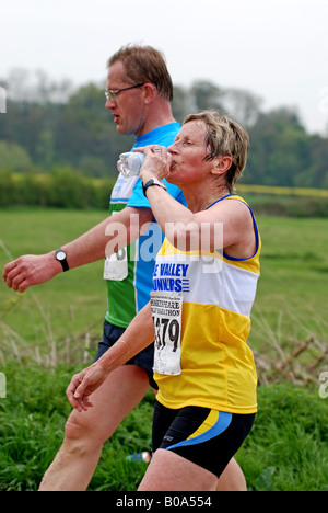 Woman in half marathon race drinking water, UK Stock Photo