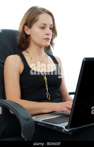 young woman in an office chair using a laptop Stock Photo