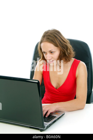 young woman in a red dress sitting in an office chair using a laptop Stock Photo