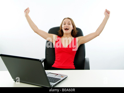 young cheering woman in a red dress working with a laptop Stock Photo