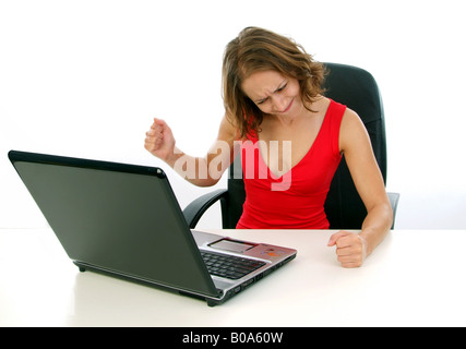 angry young woman in a red dress working at a laptop Stock Photo