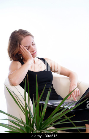 young depressed woman with laptop sitting in an armchair Stock Photo