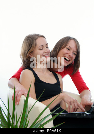 two cheerful young women using a laptop Stock Photo
