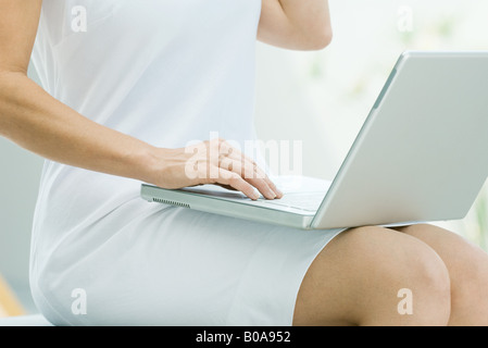 Woman sitting, using laptop computer, cropped view Stock Photo