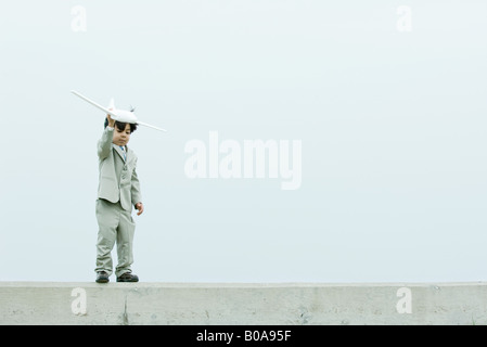 Young boy dressed in suit, holding up toy airplane Stock Photo