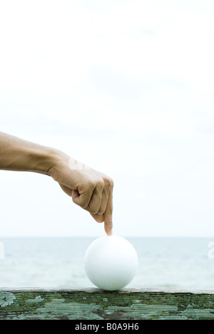 Man touching ball with index finger, cropped view of hand Stock Photo