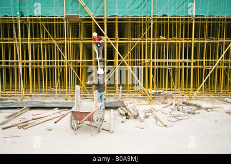Two workers assembling scaffolding on construction site Stock Photo