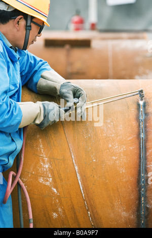 Man cutting metal with welding torch, side view, cropped Stock Photo