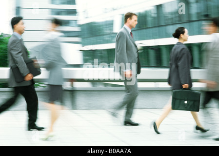 Male and female professionals walking on sidewalk, blurred motion Stock Photo