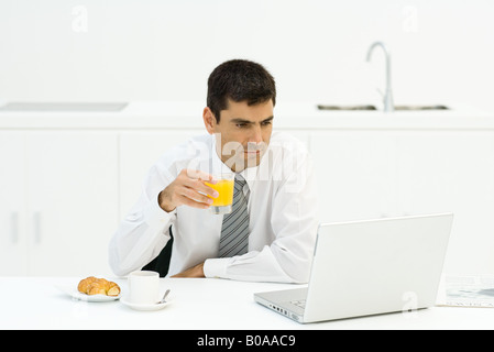 Man having breakfast and using laptop Stock Photo