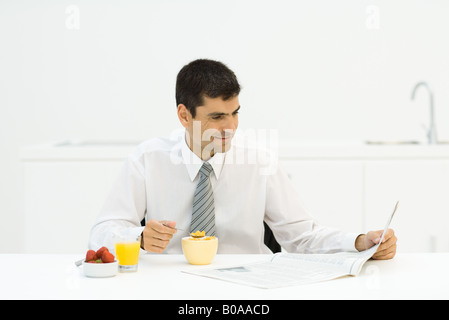 Man having breakfast in kitchen and reading newspaper Stock Photo