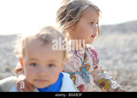 Portrait of a beautiful and tender mixed race small girl half thai hugging a baby Stock Photo