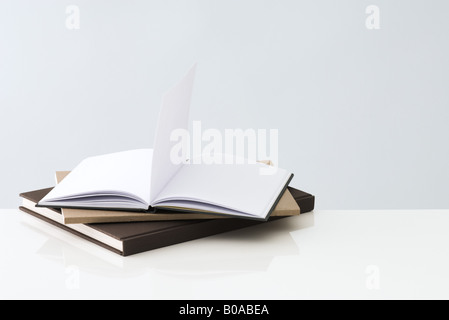 Stack of books, one open book with blank pages inside Stock Photo