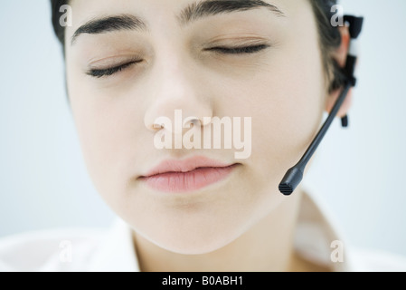 Woman wearing headset, closing eyes, close-up of face Stock Photo