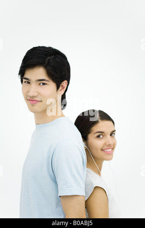 Young man and woman standing back to back, smiling at camera, portrait Stock Photo