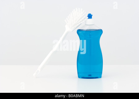 Dish brush leaning against bottle of dishwashing soap Stock Photo