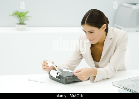 Young professional using adding machine, holding receipt Stock Photo