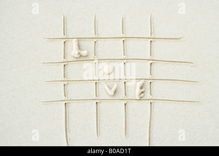 Coral shapes spelling the word 'love' on grid drawn in sand Stock Photo