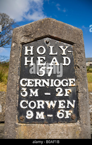 Original old milestone showing miles distance beside A5 historic coaching route to Holyhead built by Thomas Telford. Cerrigydrudion Conwy Wales UK Stock Photo