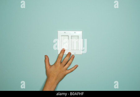 A hand touching or reaching a light switch control Stock Photo