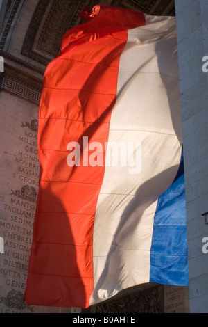 French tricolor flag flying in the setting sunlight underneath the Arc D'Triomphe, Paris, France Stock Photo