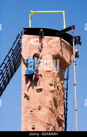 Young boy climbs a rock climbing pillar or tower in Tucson Arizona Stock Photo