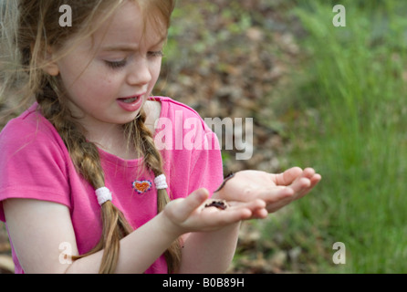 SOUTH CAROLINA YORK A beautiful young girl looking at earthworms crawling in her open hands in the middle of a forest Stock Photo