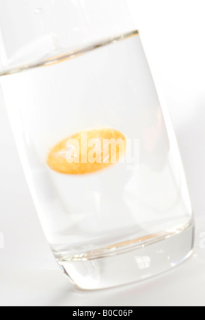Effervescent orange vitamin tablet dropped in to a glass of water Stock Photo