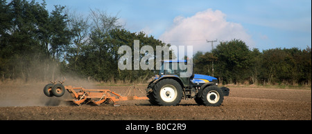 A tractor rolling fields in Cowlinge near Haverhill Suffolk Stock Photo