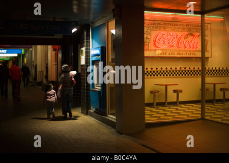 Mother and daughter walk past cafe at night Stock Photo