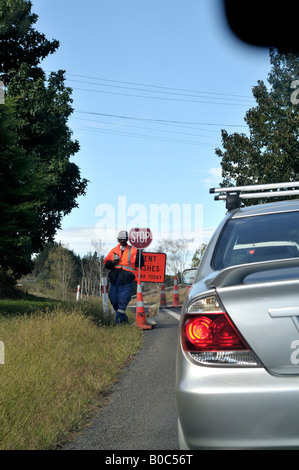 man sitting at road works with stop sign Stock Photo