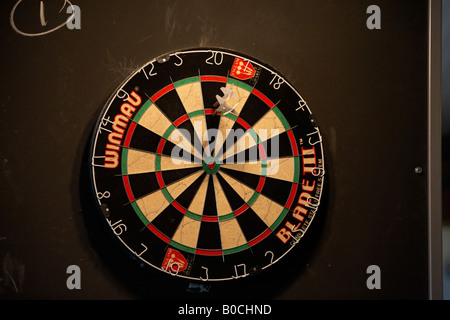 A dart board with three arrows scoring well and embedded in the circular Stock Photo
