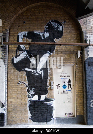 Boy stands in pot and waters his feet and flower with watering can - an image from The Cans Festival London, Banksy helped open Stock Photo