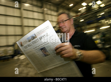 A worker checks copies of Wall Street Journal newspapers as they are printed on printing presses at Newsfax in East London U K Stock Photo