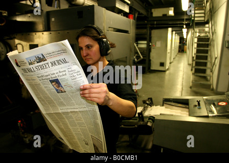 A worker checks copies of Wall Street Journal newspapers as they are printed on printing presses at Newsfax in East London U K Stock Photo