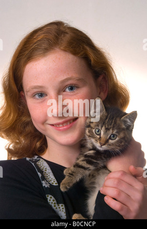 Red haired freckle faced 11 year old girl with kitten Stock Photo