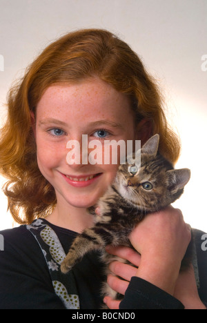 Red haired freckle faced 11 year old girl with kitten Stock Photo