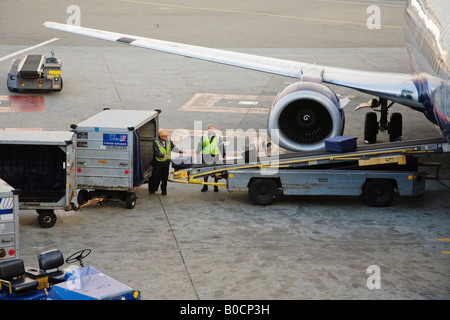Ground crew loading checked baggage onto an airplane San Francisco International Airport California USA Stock Photo
