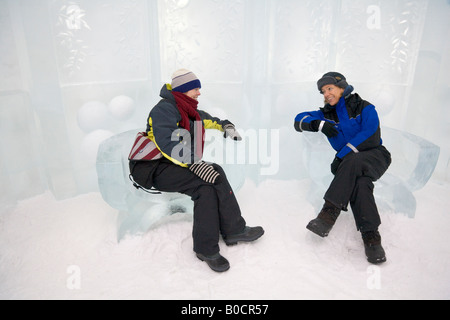 Two women are sitting on armchairs made of ice inside the Jukkasjarvi icehotel in northern Sweden Stock Photo