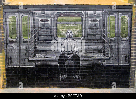 Bald man sits on tube, train - an image from The Cans Festival, a London street exhibition graffito artist Banksy helped to open Stock Photo