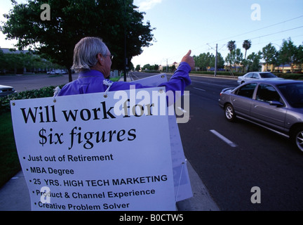 Unemployed, former marketing executive stands on a street corner in Silicon Valley holding a Sandwich board advertising himself. Stock Photo