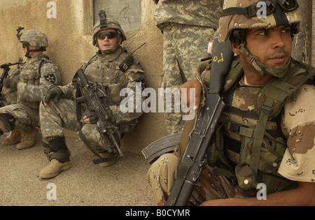 Iraqi army and U S Army soldiers takes a break while pulling security during a building clearing mission in Rashid Iraq Stock Photo