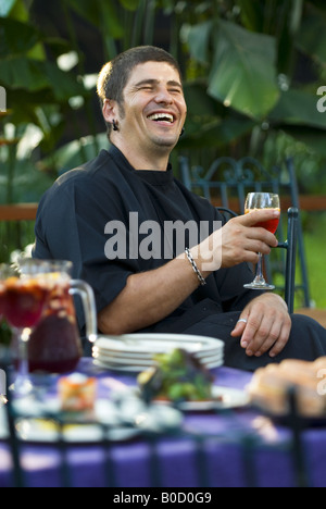 A smiling Spanish chef sits at a colorful table of Mediterranean food. Stock Photo