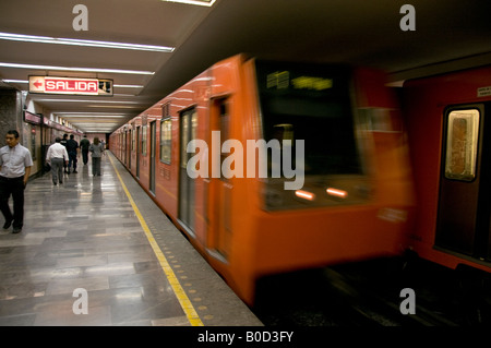 Speeding orange-coloured underground metro train in Mexico City. Showing passengers on the platform and the SALIDA - exit sign. Stock Photo