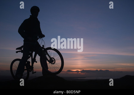 Mountain Biker standing at sunset silhouetted Stock Photo