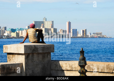 Young man sitting on the El Malecon wall admiring the view of Havana Cuba Stock Photo