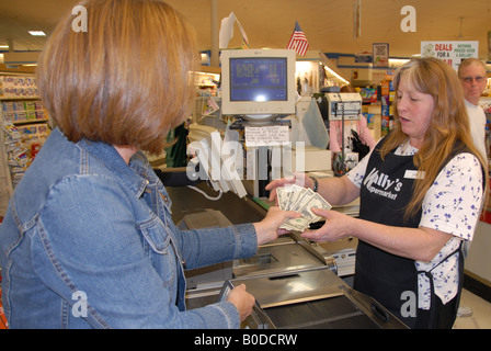 A customer gives a cashier money to pay for her groceries. Stock Photo