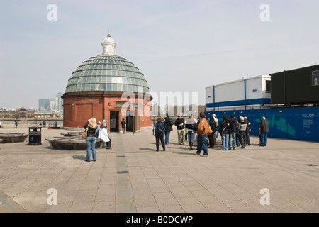 A young woman Photographs the Greenwich Foot tunnel next to a group of Tourists with a guide Stock Photo