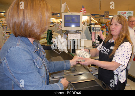 A customer gives a cashier money to pay for her groceries. Stock Photo